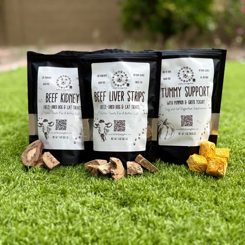 Three packages of pet food on grass with visible branding and product names.